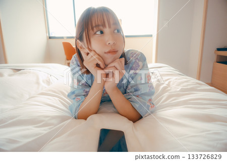 一位身穿浴衣的女子麵朝下放鬆地躺在床上。 133726829