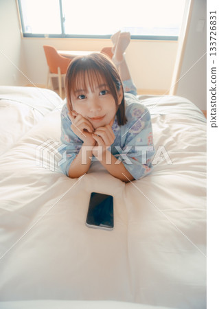 一位身穿浴衣的女子麵朝下放鬆地躺在床上。 一位身穿浴衣的女子麵朝下放鬆地躺在床上。 133726831