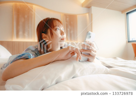 一位身穿浴衣的女子在床上放鬆的場景 133726978