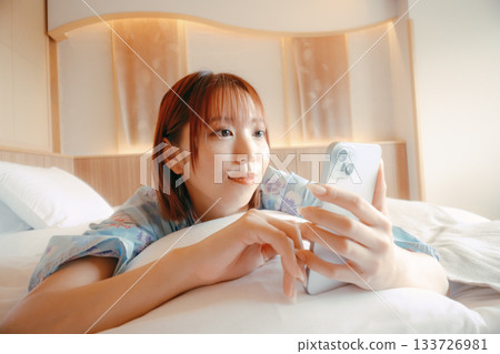 一位身穿浴衣的女子在床上放鬆的場景 133726981