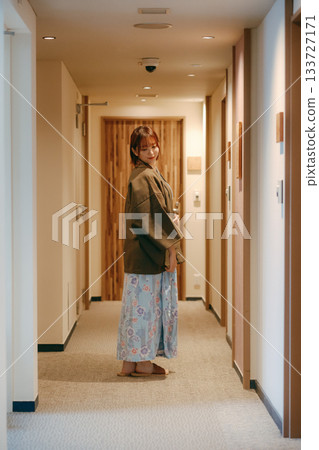 A woman in a yukata looking back in the corridor of a ryokan A woman in a yukata looking back in the corridor of a ryokan 133727171