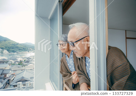 一對穿著浴衣的老夫婦正望著窗外的街景。 一對穿著浴衣的老夫婦正望著窗外的街景。 133727329