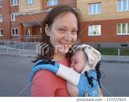 Mom Smiling with Sleeping Baby in Carrier Backpack 133727624