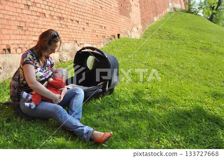 Mother Breastfeeding Baby Outdoors in Sunny Park 133727668