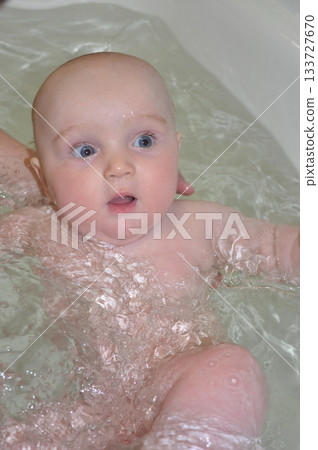 Baby Bathing in Bathtub with Curious Expression 133727670