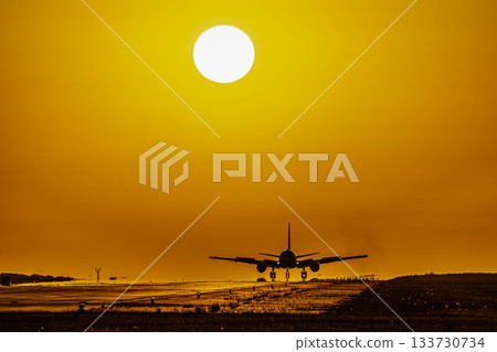 落日餘暉映照著降落的飛機 133730734
