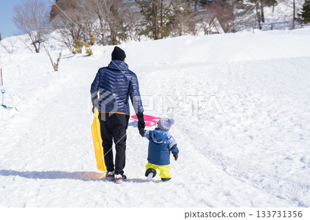 父母和孩子們在冬季的雪坡上玩耍 父母和孩子們在冬季的雪坡上玩耍 133731356