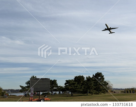 A passenger plane ascending while turning and a park A passenger plane ascending while turning and a park 133731618