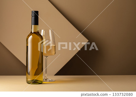 Bottle and glass of white wine on a beige background. 133732080