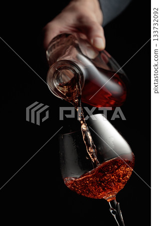 Pouring brandy in a glass goblet. Pouring brandy in a glass goblet. 133732092