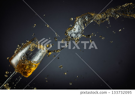 Glass and white wine splash on a black background. Glass and white wine splash on a black background. 133732095