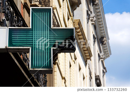 Green neon pharmacy cross with cracked glass symbolizing healthcare problems, medicine shortages, and systemic fragility Green neon pharmacy cross with cracked glass symbolizing healthcare problems, medicine shortages, and systemic fragility 133732260