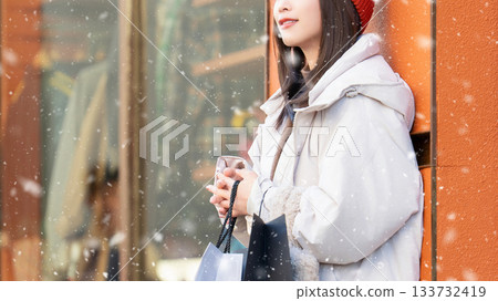 一位微笑的女子站在雪中的街角 133732419