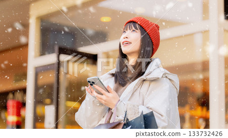 A woman using a smartphone on a snowy winter street corner A woman using a smartphone on a snowy winter street corner 133732426