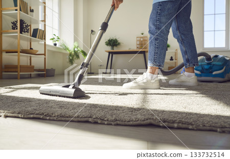 Cropped photo of woman cleaning with vacuum cleaner carpet in the living room at home. Cropped photo of woman cleaning with vacuum cleaner carpet in the living room at home. 133732514