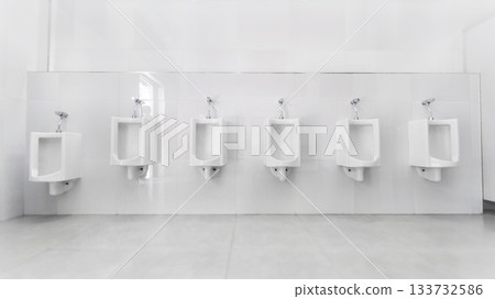 Men's room with white porcelain urinals in line. Modern clean public toilets with tiles. 133732586