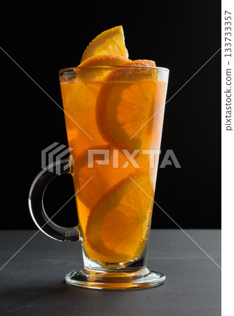 A drink with orange slices in a tall glass on a black table A drink with orange slices in a tall glass on a black table 133733357