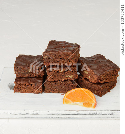 Stack of square baked slices of brownie chocolate cake with walnuts Stack of square baked slices of brownie chocolate cake with walnuts 133733411