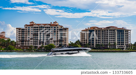 Fisher island building. Luxury boat motor yacht. Luxury yacht go to marina. Boating and yachting. Luxury lifestyle. Yacht at Fisher island luxury residential building. Vacation on summer in Miami Fisher island building. Luxury boat motor yacht. Luxury yacht go to marina. Boating and yachting. Luxury lifestyle. Yacht at Fisher island luxury residential building. Vacation on summer in Miami 133733605