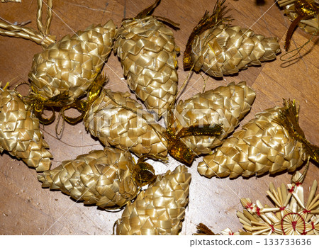 A close-up shot from above. Decorative Christmas ornaments shaped like pine cones are laid out on a dark wooden surface. 133733636