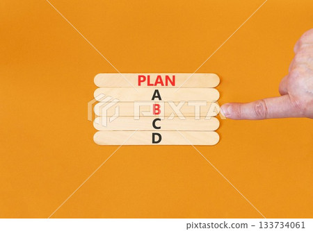 Time to plan B symbol. Concept word Plan A B C D on beautiful wooden sticks. Businessman's hand. Beautiful orange background. Business planning and time to plan B concept. Copy space. Time to plan B symbol. Concept word Plan A B C D on beautiful wooden sticks. Businessman's hand. Beautiful orange background. Business planning and time to plan B concept. Copy space. 133734061