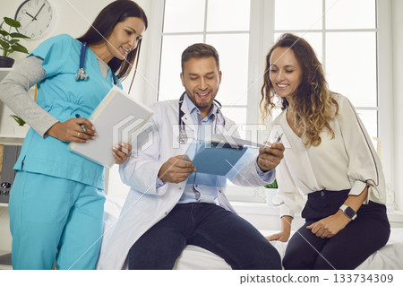 Doctor with nurse showing report file with appointment to patient giving consultation in clinic. 133734309