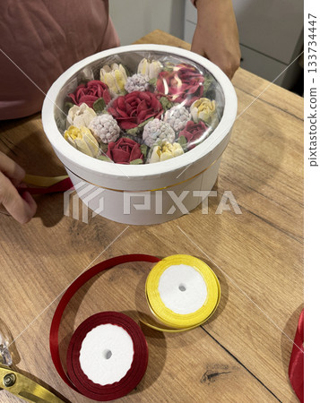 Woman packing homemade marshmallow in a hat box with transparent lid, Marshmallow flowers, tulips and roses, Packaging ribbons nearby 133734447