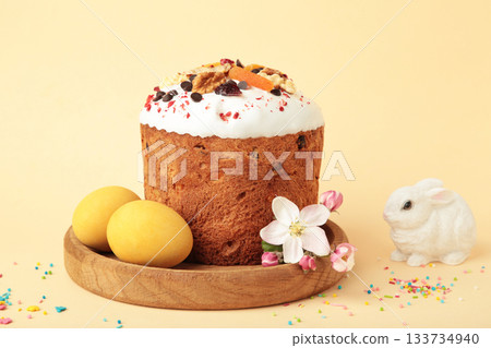 Traditional easter cakes with colorful sprinkles, with eggs, a bunny figurine, and spring flowers, creating a festive holiday scene 133734940
