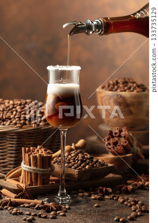 Coffee liqueur is poured from a bottle into a glass with cream. Coffee liqueur is poured from a bottle into a glass with cream. 133735129