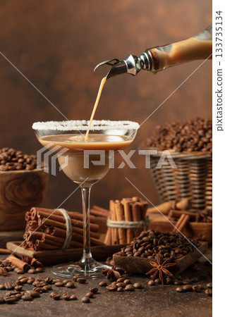 Chocolate martini cocktail or Irish cream liquor is poured from a bottle into a glass. Chocolate martini cocktail or Irish cream liquor is poured from a bottle into a glass. 133735134