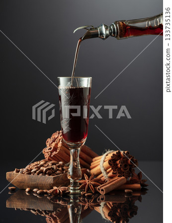 Coffee liquor is poured from a bottle into a glass. Coffee liquor is poured from a bottle into a glass. 133735136