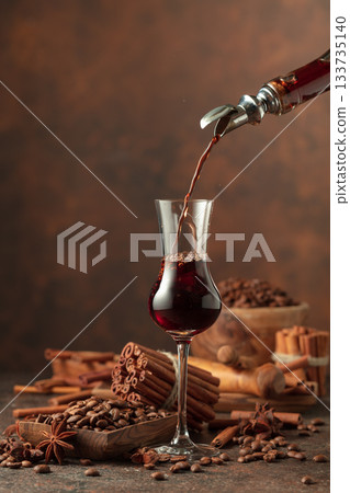 Coffee liquor is poured from a bottle into a glass. Coffee liquor is poured from a bottle into a glass. 133735140