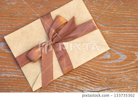Kraft certificate with a brown ribbon on a wooden background 133735302
