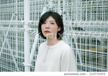 一位女子站在柵欄前。 133735455