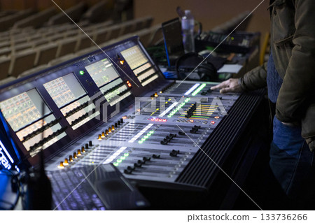 A sound engineer works at a digital mixing console at a concert. A sound engineer works at a digital mixing console at a concert. 133736266