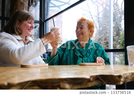 cafe drinking coffee woman and adult daughter elderly woman Portrait of old peasant woman with smiling daughter wearing typical Colombian clothes. Women with brown skin. 133736516
