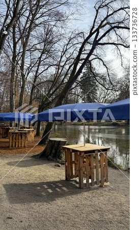 Calm Lakeside Park With Blue Umbrellas and Wooden Tables at Christmas Market in Bad Aibling 133736728