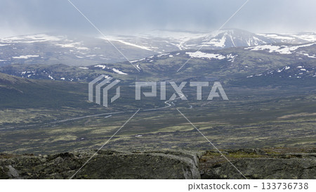 Road E6 winding through the scenic DovrefjellSunndalsfjella National Park in Norway during cloudy weather 133736738