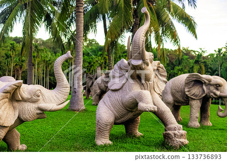 Stone sculptures of elephants in Nanshan Park, Sanya, Hainan, against a backdrop of green palm trees 133736893