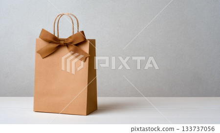Elegant Kraft Gift Bag with Decorative Brown Ribbon on Neutral Background 133737056