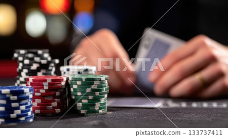 Gambler Holding Playing Cards with Stacked Poker Chips in Casino Environment 133737411