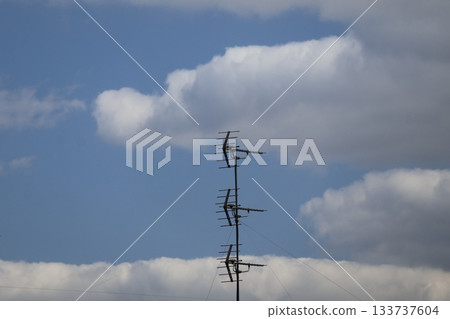 A view of white clouds, blue sky and three antennas 133737604