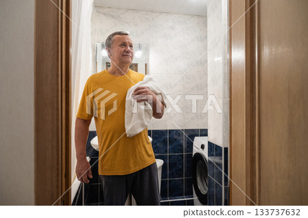 Drying face with towel before oral care, caucasian adult male standing in bathroom and preparing for morning hygiene routine. Man Brushing Teeth 133737632