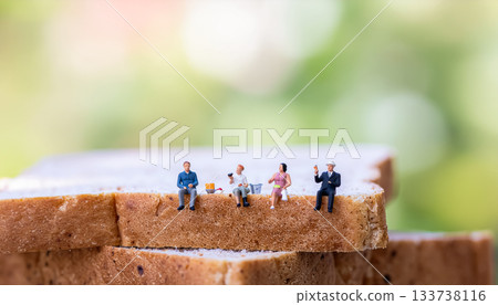 Miniature people enjoying a meal on bread / Creative graphic material that creates humor and surprise 133738116