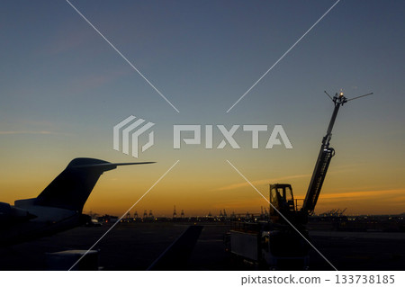 Sunset view at an airport with service equipment planes in foreground Sunset view at an airport with service equipment planes in foreground 133738185