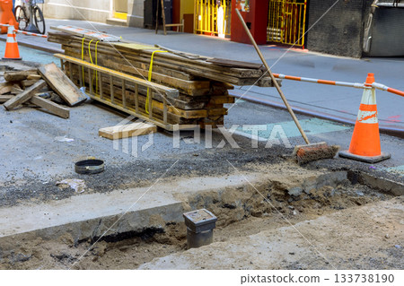 Construction work on city street involves digging materials stacked nearby for repair project Construction work on city street involves digging materials stacked nearby for repair project 133738190