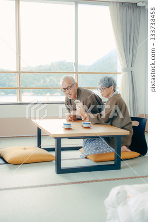 一對老年夫婦在日式旅館的房間裡一起看智慧型手機。 一對老年夫婦在日式旅館的房間裡一起看智慧型手機。 133738458