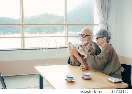 An elderly couple looking at a smartphone together in a Japanese-style room at a ryokan An elderly couple looking at a smartphone together in a Japanese-style room at a ryokan 133738462