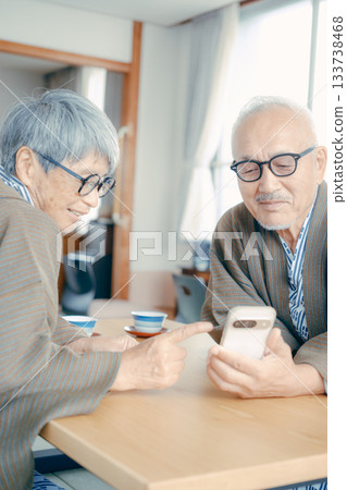 An elderly couple looking at a smartphone together in a Japanese-style room at a ryokan An elderly couple looking at a smartphone together in a Japanese-style room at a ryokan 133738468