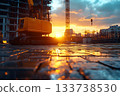 Excavator standing on a wet construction site at sunset with glowing reflections 133738530